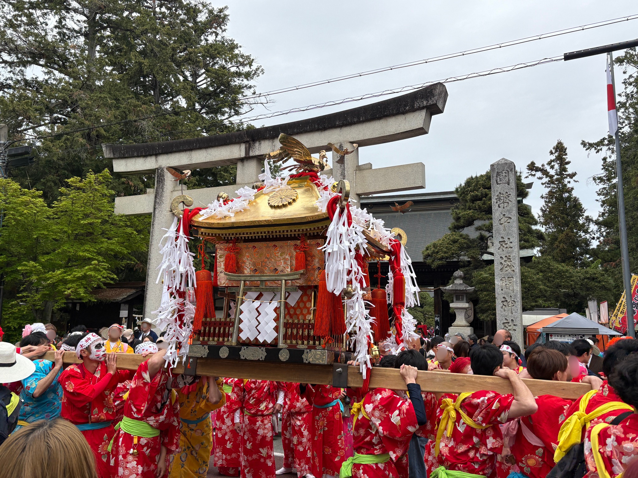 例大祭の様子。女性の装束をまとい神輿を担ぐ